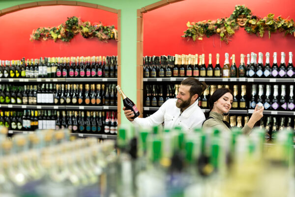 A young family, a man and a woman choose alcohol in a large supermarket A young family, a man and a woman choose alcohol in a large supermarket.